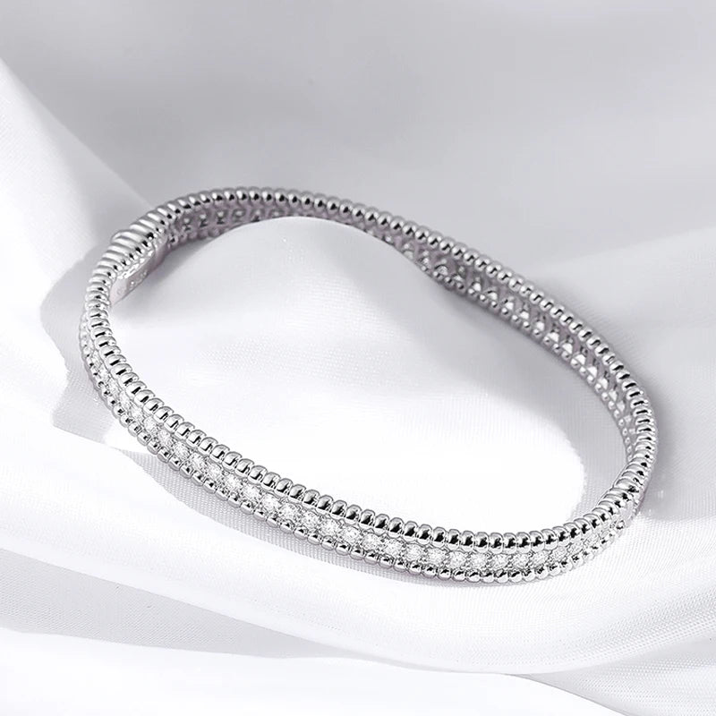 Introducing the Stella Moissanite Bangle: a luxurious piece crafted with 2.28CT of brilliant moissanite stones, set in sterling silver plated with 18K white gold in a secure 4-prong setting. Its timeless elegance and durability make it perfect for special occasions, while its superior shine rivals that of diamonds. Elevate your style with this stunning, environmentally conscious jewelry choice from Elejoux.